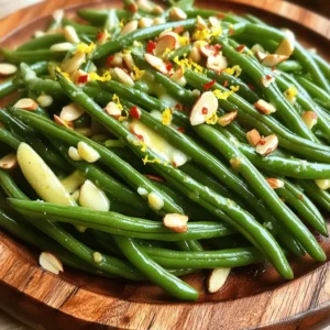 - 1 pound fresh green beans, trimmed - 4 tablespoons unsalted butter - 4 cloves garlic, minced - 1 teaspoon salt - ½ teaspoon freshly ground black pepper - ¼ teaspoon red pepper flakes (optional) - 1 tablespoon freshly squeezed lemon juice - Zest of 1 lemon - 2 tablespoons toasted almonds, chopped (for garnish) Gather these simple ingredients before you start. Fresh green beans bring a crisp taste. The unsalted butter adds richness, while garlic gives a strong flavor. Salt and pepper enhance all the tastes. Red pepper flakes add a little heat, but you can skip them if you prefer. Lemon juice and zest give a nice brightness to the dish. Finally, toasted almonds add crunch and depth. - Almonds, lemon zest - Other possible add-ins (e.g., crushed red pepper, different herbs) Feel free to mix things up! You can add different herbs like thyme or basil for more flavor. Try using other nuts, like pecans or walnuts, for a twist. Citrus zest from oranges or limes can also change the taste. The options are endless, so have fun with it! First, fill a large pot with water and add salt. Bring the water to a rolling boil. The salt helps season the beans. Once boiling, carefully add the trimmed green beans. Blanch them for about 3 to 4 minutes. You want them bright green and tender-crisp. Next, prepare an ice water bowl. After blanching, use a slotted spoon to transfer the green beans to the ice water. This stops the cooking and keeps them vibrant. Let them cool for a few minutes. Drain and set aside. Now, grab a large skillet. Heat the butter over medium heat until it melts and bubbles. This should take a minute or two. As the butter melts, add the minced garlic. Stir it constantly for about 1 minute. You want it fragrant but not brown; burnt garlic can taste bitter. Once the garlic is ready, toss in the blanched green beans. Stir well to coat them in the garlic butter. Add salt, black pepper, and red pepper flakes if you like heat. Sauté everything together for another 2 to 3 minutes. You want the beans heated through and full of flavor. Remove the skillet from the heat. Squeeze fresh lemon juice over the green beans. Sprinkle lemon zest on top as well. Toss everything together so the flavors mix well. Finally, transfer the green beans to a serving platter. Garnish with chopped toasted almonds for a nice crunch. This adds texture and flavor to your dish. Enjoy your garlic butter green beans with toasted almonds! For the full recipe, check the earlier section. When choosing green beans, look for ones that are bright green. Fresh beans should snap easily when bent. Avoid beans that look wilted or have brown spots. Firmness is key; they should feel crisp to the touch. Sourcing organic beans can enhance flavor and quality. If you find local farmers' markets, check them for fresh options! Cooking garlic properly is vital to avoid bitterness. Start with medium heat for your butter. Let it melt slowly until it bubbles. Add minced garlic and stir it constantly. This helps it cook evenly. Cook for just about one minute. You want it fragrant but not brown. If it turns brown, it tastes bitter and ruins your dish. To add more flavor, consider spices like cumin or paprika. Fresh herbs like thyme or basil can also brighten the dish. A pinch of red pepper flakes adds a nice kick. Lemon juice and zest are crucial for a zesty finish. They balance the richness of the butter. Experiment with these flavors to find your favorite twist. {{image_4}} You can add a tasty crunch to your garlic butter green beans by using nuts. Toasted almonds, pecans, or walnuts work great. To incorporate them, simply chop up your choice of nut. After sautéing the green beans, toss in the nuts for the last minute of cooking. This adds flavor and texture. You can also sprinkle nuts on top when serving for a nice look. If you want a new twist, try using lime or orange instead of lemon. Lime gives a fresh, zesty kick, while orange adds a sweet touch. To use, squeeze in the juice and add a little zest at the end. This small change can brighten the whole dish and make it feel new. Mixing in other veggies can make this dish even more colorful and nutritious. Carrots or bell peppers are great choices. Slice them thinly, and add them to the skillet with the garlic. Cook them until they soften a bit before adding the green beans. This way, you create a blend of flavors that everyone will love. To keep leftover garlic butter green beans fresh, store them in an airtight container. Make sure to refrigerate them within two hours of cooking. This helps avoid bacteria growth. They will stay good for up to three days in the fridge. Before sealing, allow them to cool slightly. This prevents moisture buildup, which can make them soggy. To reheat your green beans, use the stove or microwave. For the stove, place them in a skillet over medium heat. Add a splash of water or a bit of butter for moisture. Stir often until they are heated through. If using the microwave, cover them with a damp paper towel. Heat in 30-second bursts, stirring between each. This keeps them tender and flavorful. If you want to freeze green beans, first blanch them. Boil them for 3-4 minutes, then cool in ice water. Drain them well to remove excess water. Pack the green beans into freezer bags, removing as much air as possible. Label the bags with the date. They can stay frozen for up to six months. When ready to use, thaw them overnight in the fridge or cook them straight from the freezer. This way, you can enjoy this dish later! To prepare green beans, start by rinsing them under cold water. This removes dirt and debris. Next, trim the ends. You can snap them off with your fingers, or use a knife for a clean cut. I prefer to use fresh, firm green beans for the best taste. Yes, you can use frozen green beans. They are convenient and save time. However, they may not have the same crispness as fresh beans. Frozen beans also require a different cooking time. Make sure to thaw them before cooking. Garlic butter green beans pair well with many dishes. They go great with grilled chicken or fish. You can also serve them with steak or roasted veggies. For a lighter meal, try them with a fresh salad. Garlic butter green beans last about 3 to 4 days in the fridge. Store them in an airtight container. Always check for freshness before eating. If they smell off or look slimy, it’s best to throw them away. For the full recipe, check out Garlic Butter Green Beans with Toasted Almonds. In this article, I covered how to make delicious garlic butter green beans. We discussed essential and optional ingredients, step-by-step cooking instructions, and some helpful tips. You learned about enhancing flavors and storage best practices. These green beans are easy to prepare and delicious. With variations, you can make this dish your own. Enjoy these tasty green beans as a side or mix them with other vegetables!