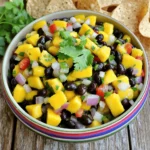 To make this tasty mango black bean salsa, you will need: - 1 ripe mango, diced into small cubes - 1 cup canned black beans, thoroughly rinsed and drained - 1/2 medium red bell pepper, finely chopped - 1/2 medium red onion, finely chopped - 1 jalapeño pepper, seeds removed and minced (optional for a kick of heat) - 1/4 cup fresh cilantro, roughly chopped - Juice of 2 limes, freshly squeezed - 1 tablespoon extra-virgin olive oil - Sea salt and freshly ground black pepper to taste This mix of fresh and vibrant ingredients gives the salsa its fresh taste. Each bite bursts with flavor and color. You can make swaps if you can't find some ingredients. - Mango: Try peaches or pineapple for a different sweetness. - Black Beans: Kidney beans or pinto beans work well too. - Red Bell Pepper: Yellow or orange bell peppers can brighten your dish. - Red Onion: Use green onions for a milder flavor. - Jalapeño: If you want less heat, skip it or use a green bell pepper. - Cilantro: Parsley or basil can replace cilantro for a different herb taste. These substitutions still create a delicious salsa. This salsa is not just tasty; it's also good for you. - Calories: About 150 calories per serving - Protein: 6 grams from the beans - Fiber: 5 grams, helping digestion - Vitamin C: High from mango and lime - Fat: Low, with healthy fats from olive oil This salsa is a great choice for a healthy snack or a meal topper. Its bright flavors and nutrients can fit well into many diets. You can find the full recipe [here]. To make mango black bean salsa, start by gathering all your ingredients. You need one ripe mango, one cup of canned black beans, half a red bell pepper, half a red onion, and one jalapeño pepper. 1. First, dice the mango into small cubes. Make sure they are not too big. 2. Rinse and drain the black beans. This step removes excess salt and liquid. 3. Finely chop the red bell pepper and the red onion. Keep the pieces small for easy eating. 4. If you like heat, remove the seeds from the jalapeño and mince it finely. 5. Place all these ingredients into a large mixing bowl. When mixing your salsa, be gentle. You want to keep the mango cubes intact. After adding the chopped cilantro, lime juice, and olive oil, use a soft hand to toss everything. - Move your spatula from the bottom to the top. - Turn the bowl as you mix to ensure even distribution. - Avoid pressing down on the mango pieces, or they will turn mushy. Chilling your salsa enhances its taste. Once mixed, cover the bowl with plastic wrap or a lid. Place it in the refrigerator for at least 30 minutes. - This resting time allows the flavors to blend. - You can chill it longer if you wish. Just check it before serving. For the full recipe, refer to the [Full Recipe]. Enjoy your fresh and flavorful salsa! To find the best mangoes, look for ones that are slightly soft. Gently press the mango with your fingers. If it gives a little, it's ripe. The color can vary, so check for a sweet smell at the stem. This means it’s ready to eat. Avoid mangoes with dark spots or wrinkles. For the best taste, use fresh mangoes in your salsa. If you want more heat, add more jalapeño. Keep the seeds if you like it spicy. For less heat, use less jalapeño or remove all the seeds. You can also try adding a pinch of cayenne pepper to spice it up. Taste as you go to get the right balance. To boost flavor, try adding diced avocado or chopped green onions. Fresh mint or basil can add a unique twist. For a tangy kick, mix in a little cumin or smoked paprika. These small changes can make your salsa even more exciting. Experiment with different herbs to find your favorite mix. {{image_4}} You can mix in other fruits or veggies to make the salsa unique. Try adding diced pineapple for a sweet punch. Chopped avocado adds creaminess and a rich texture. You could also include diced cucumber for a refreshing crunch. Each fruit or vegetable gives a new taste and makes the salsa fun. Mango black bean salsa pairs well with many meats and seafood. Grilled chicken is a great choice, adding a smoky flavor. It also tastes amazing on grilled fish, like salmon or tilapia. If you like shrimp, try it with shrimp tacos. The salsa adds brightness and a burst of flavor to any dish. While lime juice and olive oil are classic, you can switch it up. Try adding a splash of orange juice for sweetness. A drizzle of balsamic vinegar gives a tangy twist. You can also season with cumin or smoked paprika for depth. Experimenting with different dressings and spices can create a salsa that fits your taste perfectly. For the full recipe, check out the Mango Black Bean Fiesta Salsa. To store leftover salsa, place it in an airtight container. Make sure the lid fits snugly. This keeps air out and helps the salsa stay fresh. You can store it in the fridge for up to three days. Just remember to give it a stir before serving again. This helps mix any ingredients that may have settled. Freezing salsa is a great way to keep it longer. Use a freezer-safe container or bag. Leave some space at the top, as the salsa will expand when it freezes. You can freeze it for up to three months. To defrost, place it in the fridge overnight. Stir it well before serving to make sure it's mixed. Fresh salsa can last in the fridge for about three days. If you see any mold or smell a sour odor, it’s time to toss it. If the salsa looks watery or has changed color, those are also signs it has spoiled. Always trust your senses! If it doesn’t look or smell right, don’t eat it. You can serve this salsa with many dishes. It pairs well with grilled chicken or fish. It also works great with tacos or as a dip with tortilla chips. You can even use it on top of salads for a fresh touch. The bright flavors of the salsa enhance any meal. The salsa lasts about 3 to 5 days in the fridge. Make sure to store it in an airtight container. The flavors may blend and taste even better after a day. However, the mango may become softer over time, so enjoy it fresh! Yes, you can make this salsa ahead of time. In fact, it tastes better if you let it chill for at least 30 minutes. This time helps the flavors mix well together. Just remember to store it in the fridge until you’re ready to serve. You can use other beans like pinto or kidney beans. These choices bring a different flavor and color. Chickpeas are also a fun option, adding a nice texture. Feel free to experiment and find your favorite bean combination! This blog post covered everything you need for Mango Black Bean Salsa. We explored ingredients, variations, and storage tips. You learned how to make salsa that shines in taste. Remember, fresh ingredients boost flavor. Adjust spiciness to fit your taste buds. Store leftovers well to keep it fresh. This salsa is perfect for parties or snacks. Now that you are equipped with this knowledge, it’s time to enjoy your delicious creation!